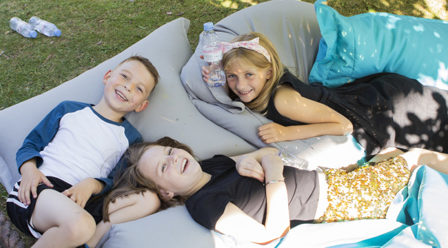Three children sat outside on cushions. Credit: Naomi Williams