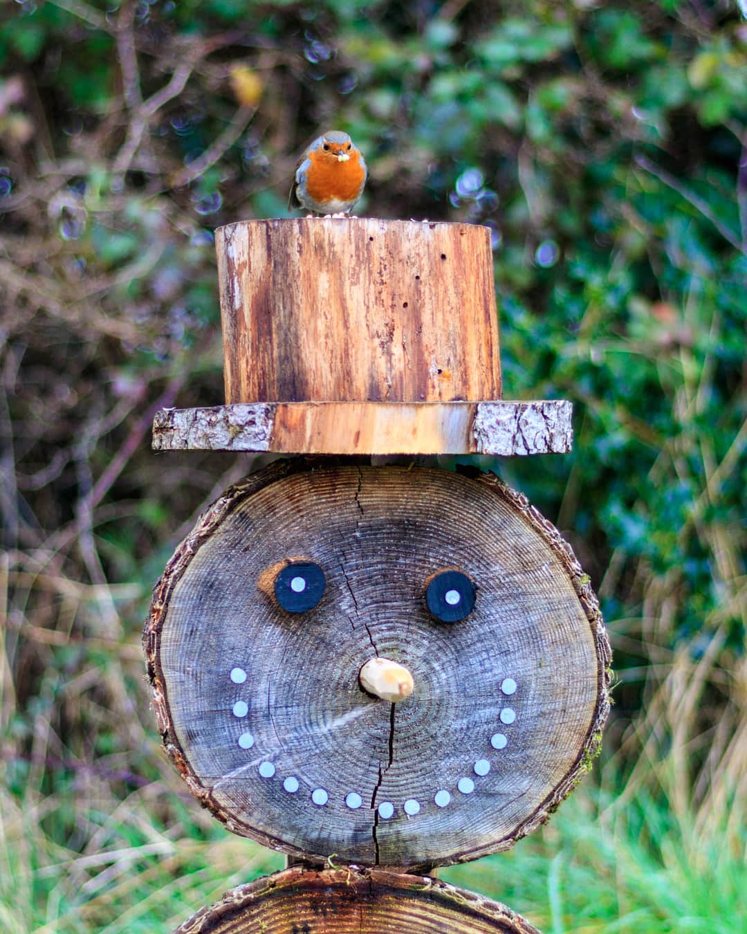 A wooden snowman with a robin perching on top
